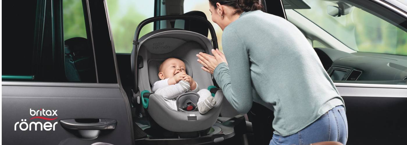 mama colocando a su bebé en una silla giratoria Britax Romer